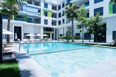 a swimming pool in front of a building with palm trees at Elegant Comfort Pool Gym & Kids Club in Mohammedia