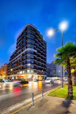 a tall building with a palm tree in front of a street at La Corniche - Seaside - Hassan II in Casablanca