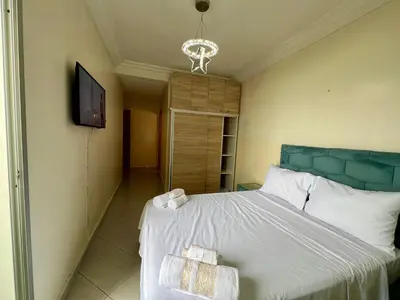 a bedroom with a bed with a blue headboard and a television at Urban Comfort Casablanca - 3BR Family Apartment in Casablanca