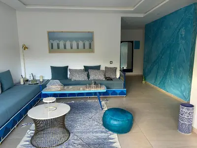 a living room with a blue couch and a table at The Blue Beach apartment- Residence Skhirat Beach2 in Skhirat