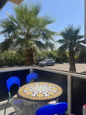 a table and chairs on a balcony with a palm tree at Bel Appart dans une résidence balneaire in Tamaris