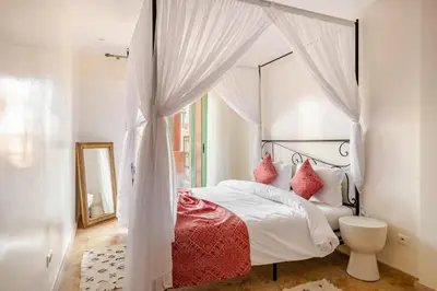 a white bedroom with a canopy bed with red pillows at Harcay CFC in Casablanca