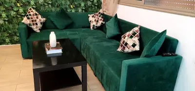 a green couch with pillows and a candle on a table at Mansouria Appartement avec Piscine à proximité de la Plage in Mansouria