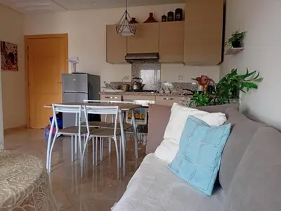 a living room with a couch and a kitchen at residence ramo flores in Bir Jedíd Saint-Hubert