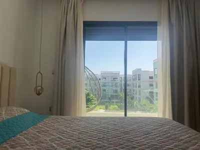 a bedroom with a bed and a large window at Beautiful appart with pool in Bouznika