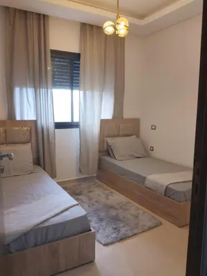 a bedroom with two beds and a window at Beautiful appart with pool in Bouznika