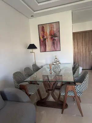 a dining room with a glass table and chairs at Beautiful appart with pool in Bouznika