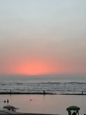 a sunset over the ocean with people on the beach at Appartement pour la CAN, Palm Beach - Mansouria in Mohammedia