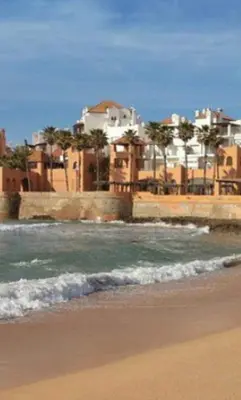 a beach with the ocean and buildings in the background at Appartement neuf avec piscine in Bouznika