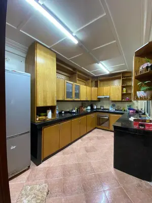 a large kitchen with wooden cabinets and a white refrigerator at Très bel Appartement A Darbouazza Tamaris in Tamaris