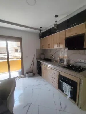 a kitchen with wooden cabinets and a marble floor at Nid d'anges in Bouznika