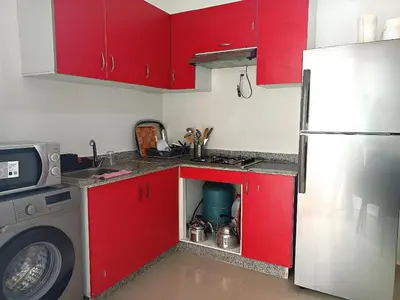 a kitchen with red cabinets and a washing machine at Kridarek - Bel appartement avec piscine in Sidi Rahal