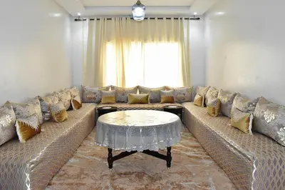 a living room with a large couch with a table at Kridarek - Bel appartement avec piscine in Sidi Rahal