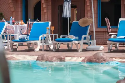 a person laying in chairs in a swimming pool at Lakala Complexe Touristique in O Ben Slimane