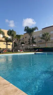 a large blue swimming pool in front of a building at Appart Coquette à Tamariss in Tamaris