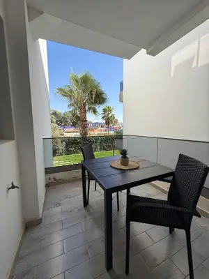 a dining room with a table and chairs and a palm tree at Appartement Moderne 2 chambres à Blanca Beach Sidi Rahal in Sidi Rahal