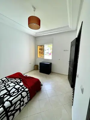 a bedroom with a bed and a television in it at Appartement à Sidi Rahal Piscine et Accès direct plage in Sidi Rahal