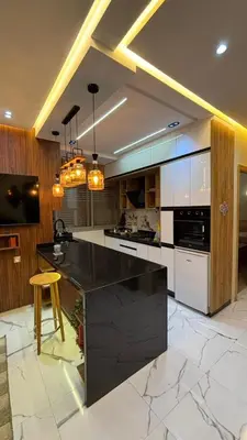 a large kitchen with a black counter and a stool at Studio lux in Bouznika