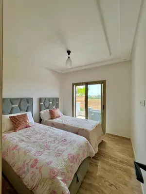two beds in a white room with a window at Heaven Beach Sidi Rahal in Sidi Rahal