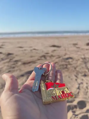 a person holding a house key in their hand on the beach at Heaven Beach Sidi Rahal in Sidi Rahal