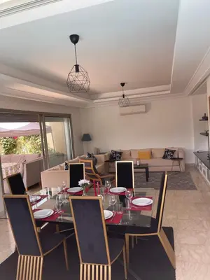 a dining table and chairs in a living room at Villa a darbouaza in Dar Bouazza