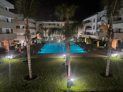 an image of a swimming pool at night with palm trees at Luxury apartment in Mansouria in Mansouria