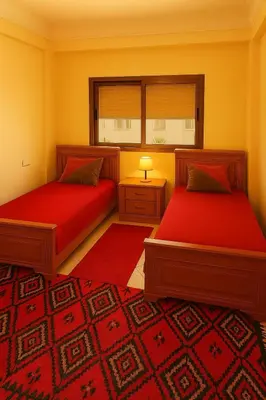 a bedroom with two beds and a red carpet at Résidence calme 3 chambres pour votre hébergement in Bouznika