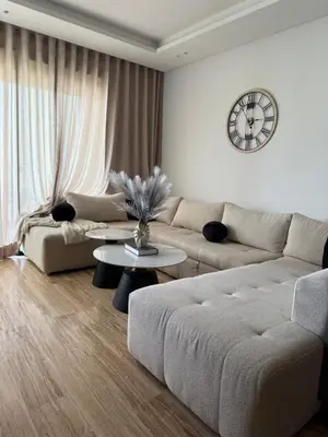 a living room with a couch and a clock on the wall at Appartement Haut Standing vue Piscine in Sidi Rahal