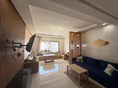 a living room with a blue couch and a tv at Appartement Residence Mansbay - Piscine - Accès Plage - WIFI in Mohammedia
