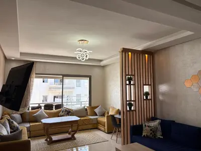 a living room with a couch and a tv at Appartement Residence Mansbay - Piscine - Accès Plage - WIFI in Mohammedia