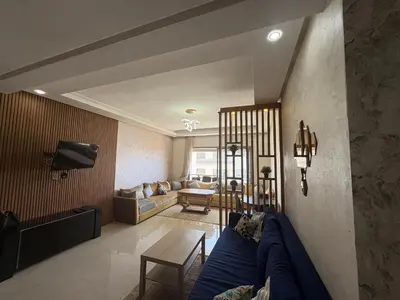 a living room with a blue couch in a room at Appartement Residence Mansbay - Piscine - Accès Plage - WIFI in Mohammedia