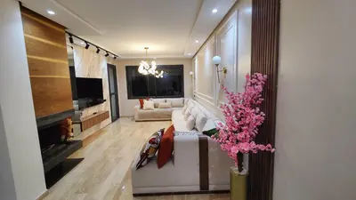 a living room with a white couch and a tv at Appartement de prestige à Dar bouazza avec plusieurs piscines et à proximité à la plage in Tamaris