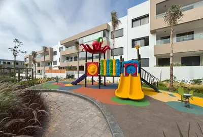 a playground in front of a building at Appartement de prestige à Dar bouazza avec plusieurs piscines et à proximité à la plage in Tamaris