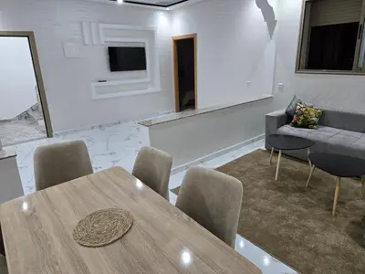 a room with a table and chairs and a couch at Appart Bouznika neuf in Bouznika