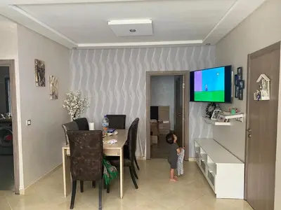 a child standing in front of a table in a room at Beach apartment in Bouznika