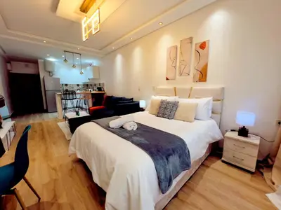 a bedroom with a large bed and a living room at Cosy studio Steps to Shore and Tramway in Rabat