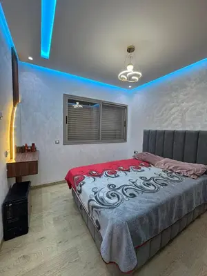 a bedroom with a large bed with blue lights on it at Cozy studio in Bouznika