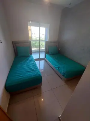 two beds sitting in a room with a window at Appartement lux a mansoria les terrasses 2 et 3 in Mansouria