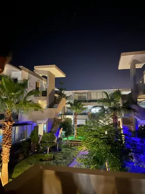 a view of a building at night with palm trees at Blanca beach in Sidi Rahal