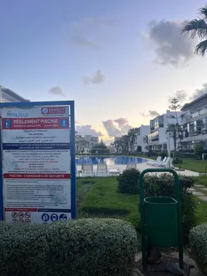 a sign in a park next to a swimming pool at Blanca beach in Sidi Rahal
