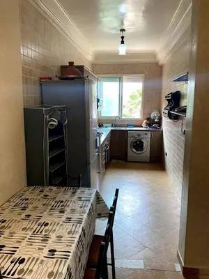 a small kitchen with a table and a refrigerator at Appartement a louer a mansouria rico flores in O Ben Slimane