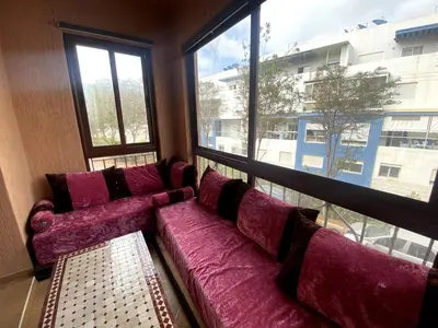a large purple couch in a room with a large window at Appartement a louer a mansouria rico flores in O Ben Slimane