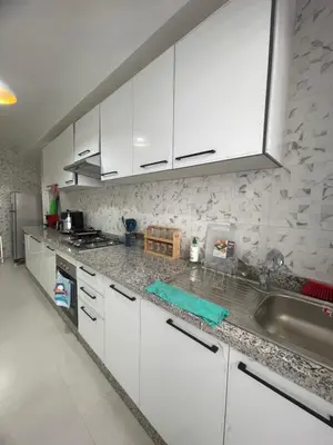 a kitchen with white cabinets and a sink at Luxueux appartement a harhoura près de la mer in Temara
