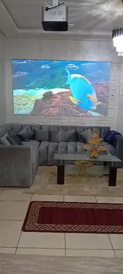 a living room with a couch and a large screen at Modern and comfortable apartment in mohammedia in Ben Yakhlef