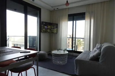 a living room with a couch and a table and windows at Calm and lovely appartement well located in Casablanca
