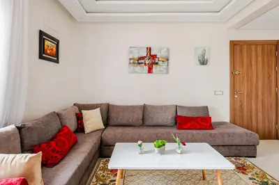 a living room with a couch and a table at Grand Appartement de standing sécurisé, proche plage avec piscine privée in Bouznika