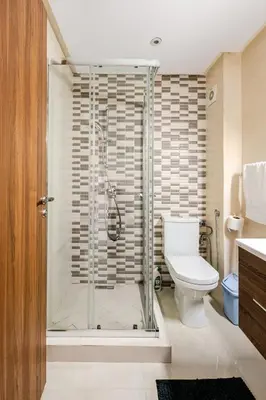 a bathroom with a shower with a toilet and a sink at Grand Appartement de standing sécurisé, proche plage avec piscine privée in Bouznika