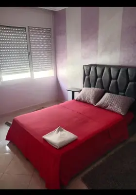 a bedroom with a red bed with a red blanket at Casablanca in Bouznika