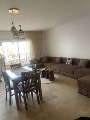 a living room with a couch and a table and chairs at Appartement vu sur piscine à 5 minutes de la plage in Mansouria