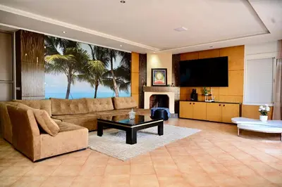 a living room with a couch and a tv at Appartement de Luxe - Piscine et Accès à la Plage in El Harhoura